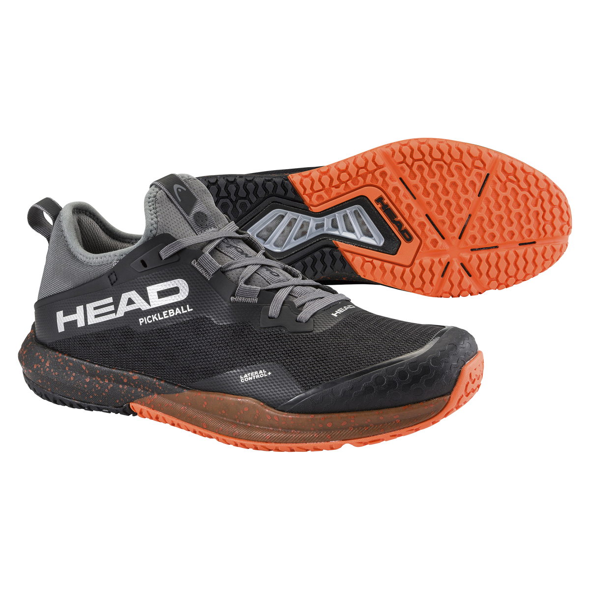 Product image of the HEAD Motion Pro Pickleball shoe in black and gray with orange accents, featuring a breathable mesh upper, reinforced toe area, lateral support structure, and a high-traction orange rubber outsole, shown from side and bottom views.