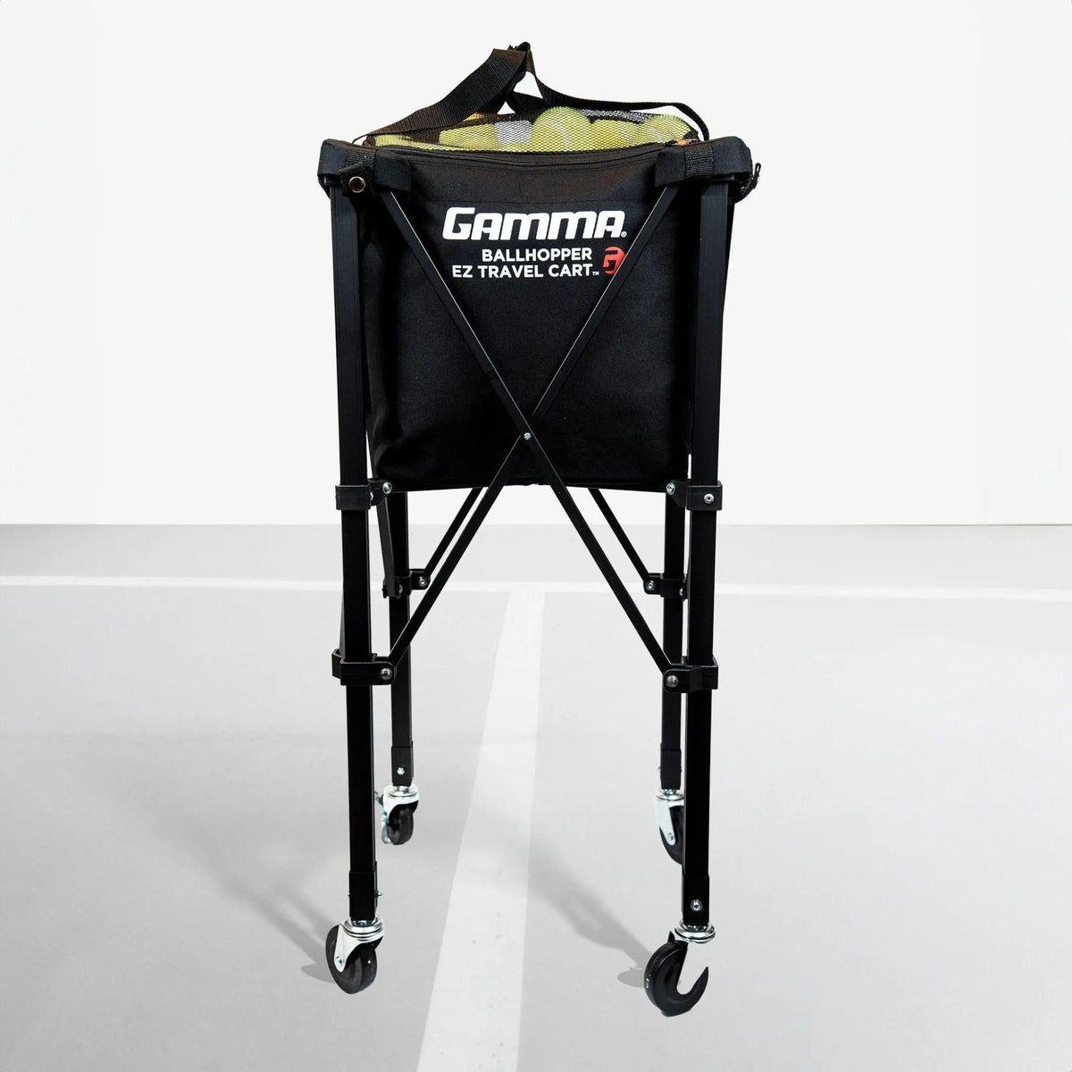Portable ball hopper cart with rolling wheels, collapsible frame, and attached storage basket for transporting sports balls.