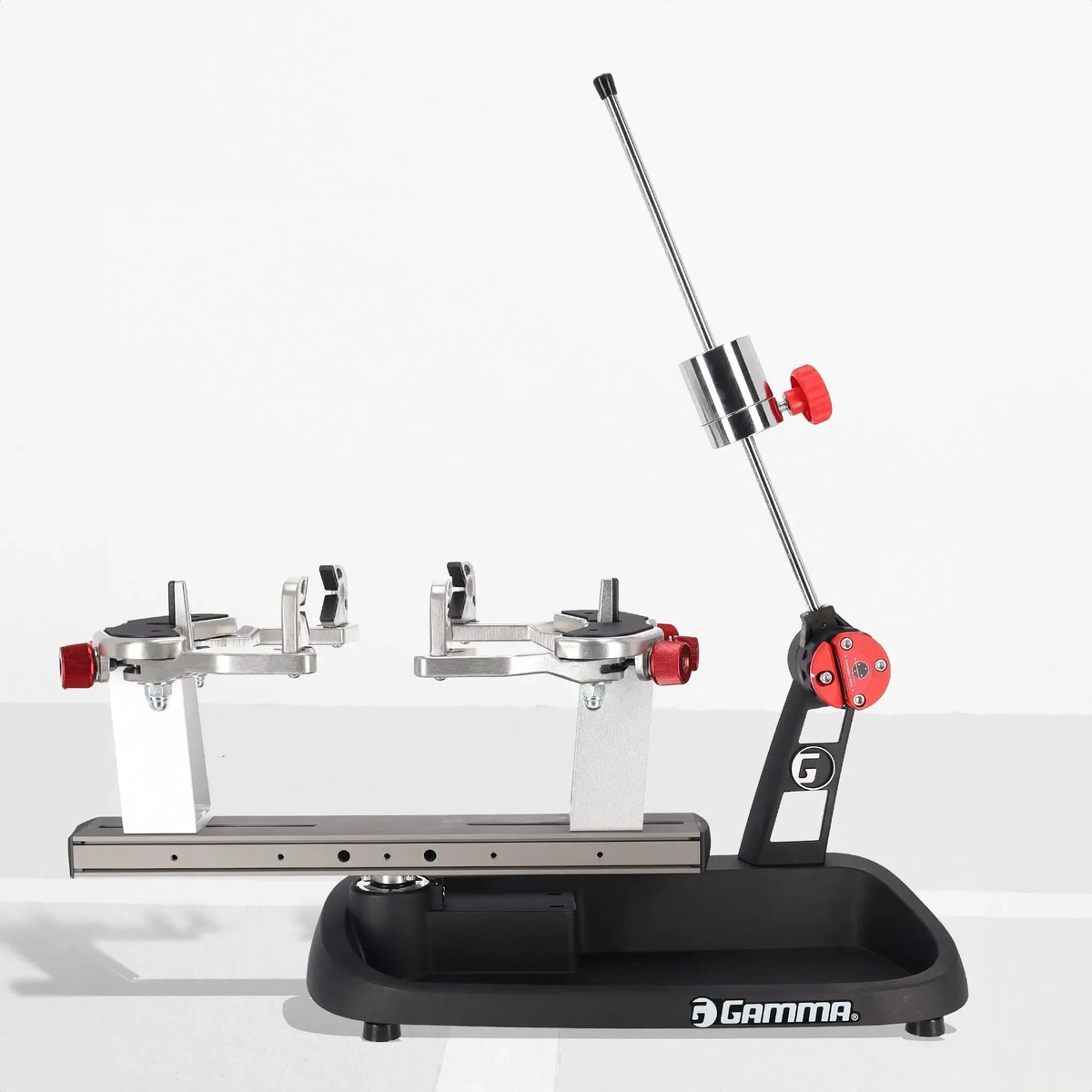 Manual drop weight stringing machine with a base platform, adjustable tension arm, and dual mounting supports with clamp system for securing racquets during stringing.