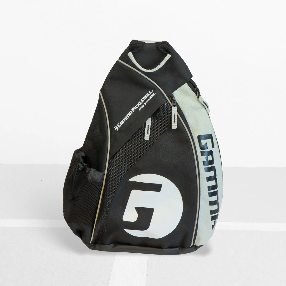 Pickleball sling bag with multiple compartments, mesh pocket, and side holder for carrying paddles, balls, and accessories.