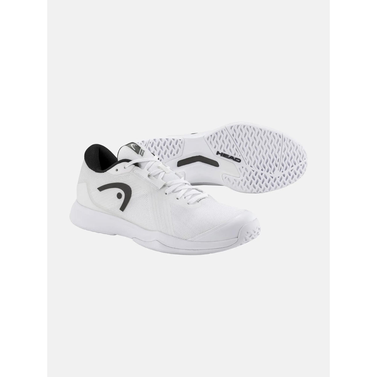 Product image of a white HEAD Sprint Team tennis shoe with black logo and accents, shown with one shoe angled forward and the other displaying the outsole tread, highlighting the lightweight mesh upper, cushioned midsole, and non-marking sole on a clean white background.
