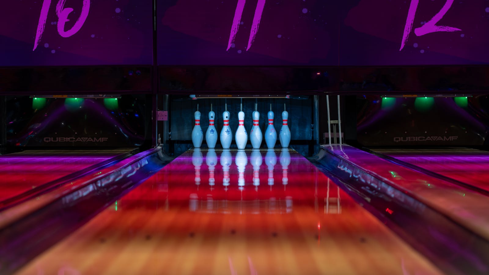 Neon bowling lane with pins set in bright house lighting