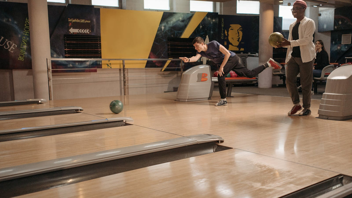 Two bowlers mid-throw at a tournament lane