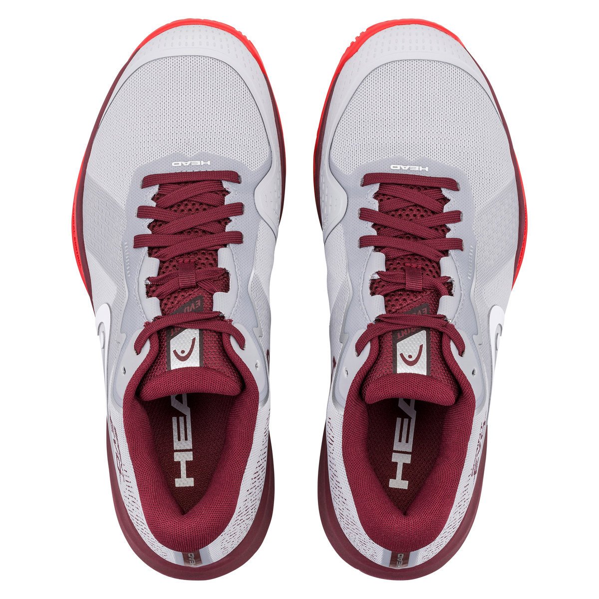 Product image of a HEAD Sprint Evo men’s tennis shoe on a black background, showing one shoe in side profile with a light grey mesh upper, burgundy collar and laces, white HEAD logo, and supportive midsole, alongside a second shoe angled to display the red non-marking herringbone outsole designed for court traction.