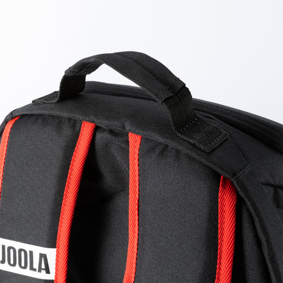 Black backpack with red straps and a visible brand logo on a light gray background
