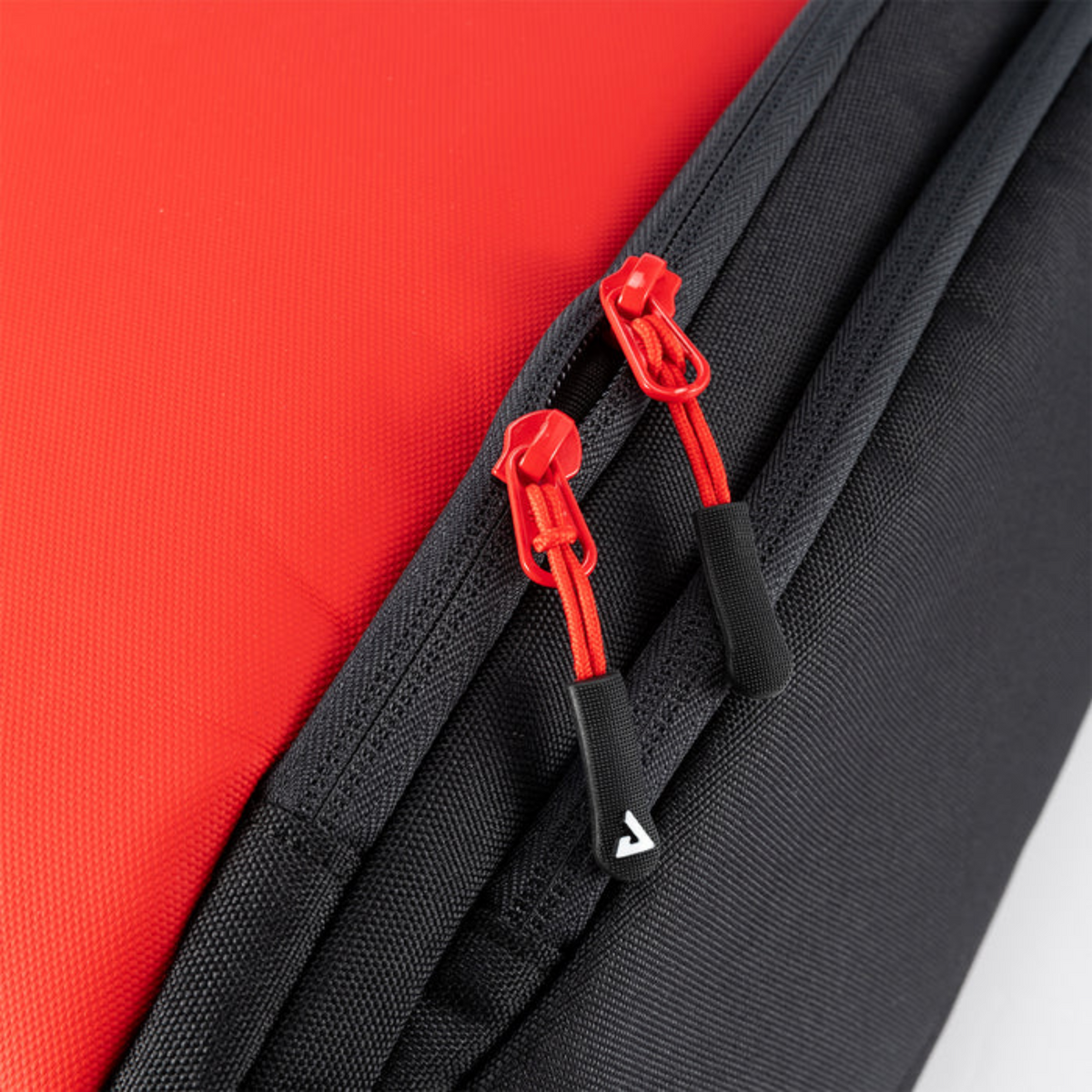 Close-up of a black bag with red zippers on a red background