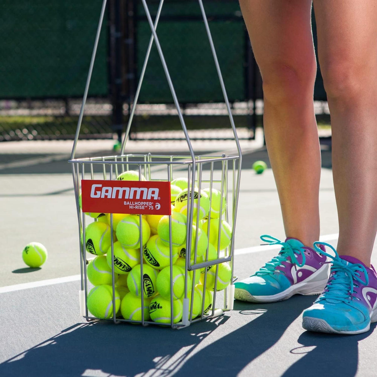 Ball hopper basket with a wire frame and elevated stand, filled with balls for easy access and organized storage during practice.