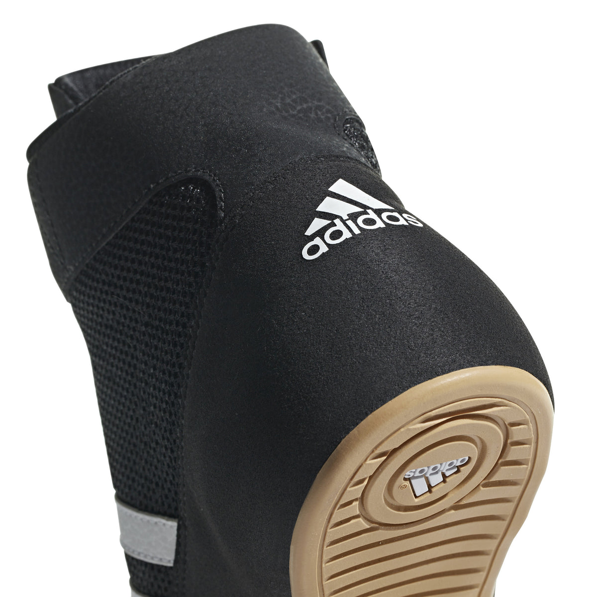 Black high-top wrestling shoe with a breathable mesh upper, black laces, padded ankle strap, and three white diagonal stripes on the side; shown from side and sole views, featuring a tan gum rubber outsole with circular traction patterns and Adidas logo for grip, stability, and mat control.