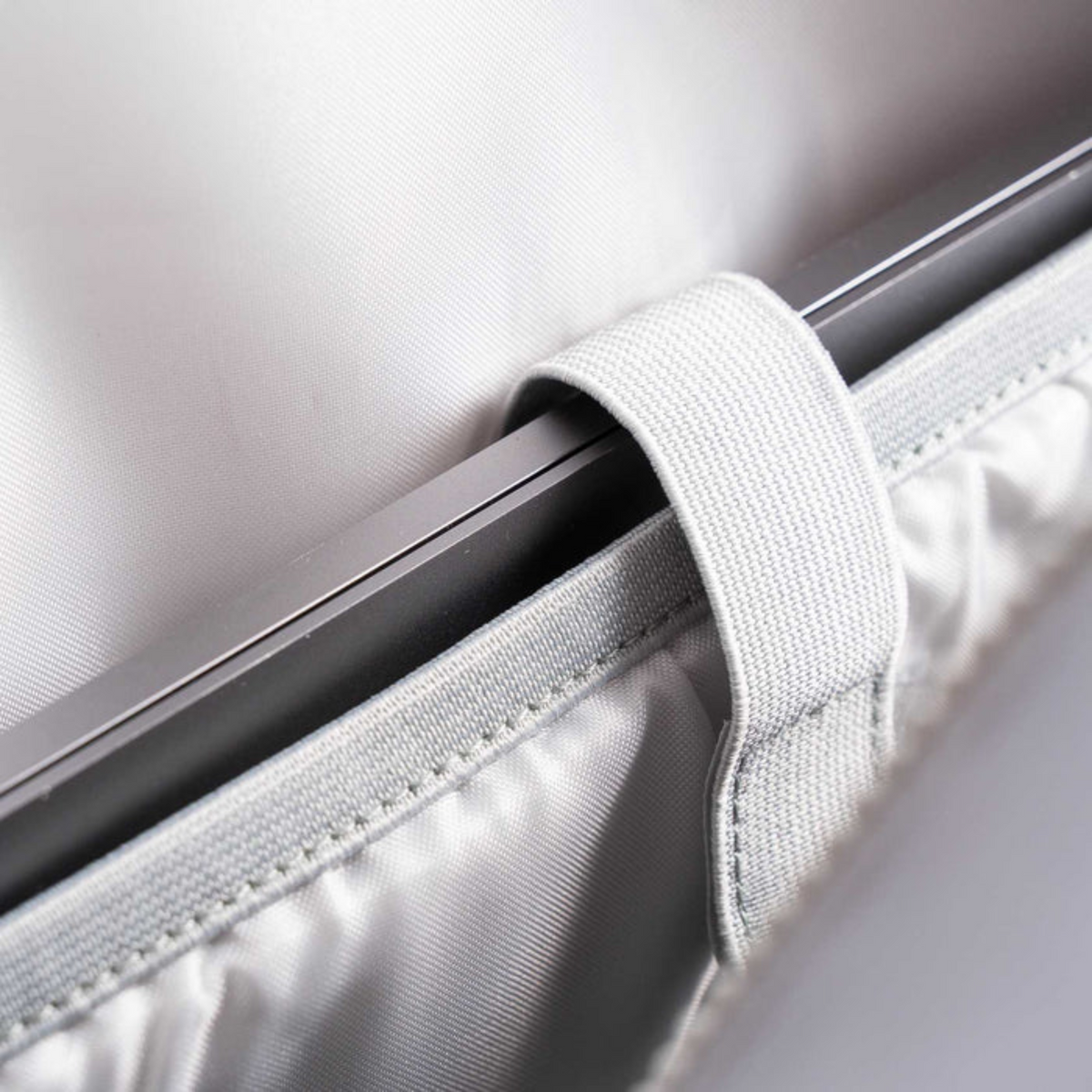 Close-up of a car window shade with a strap, showing texture and material details.