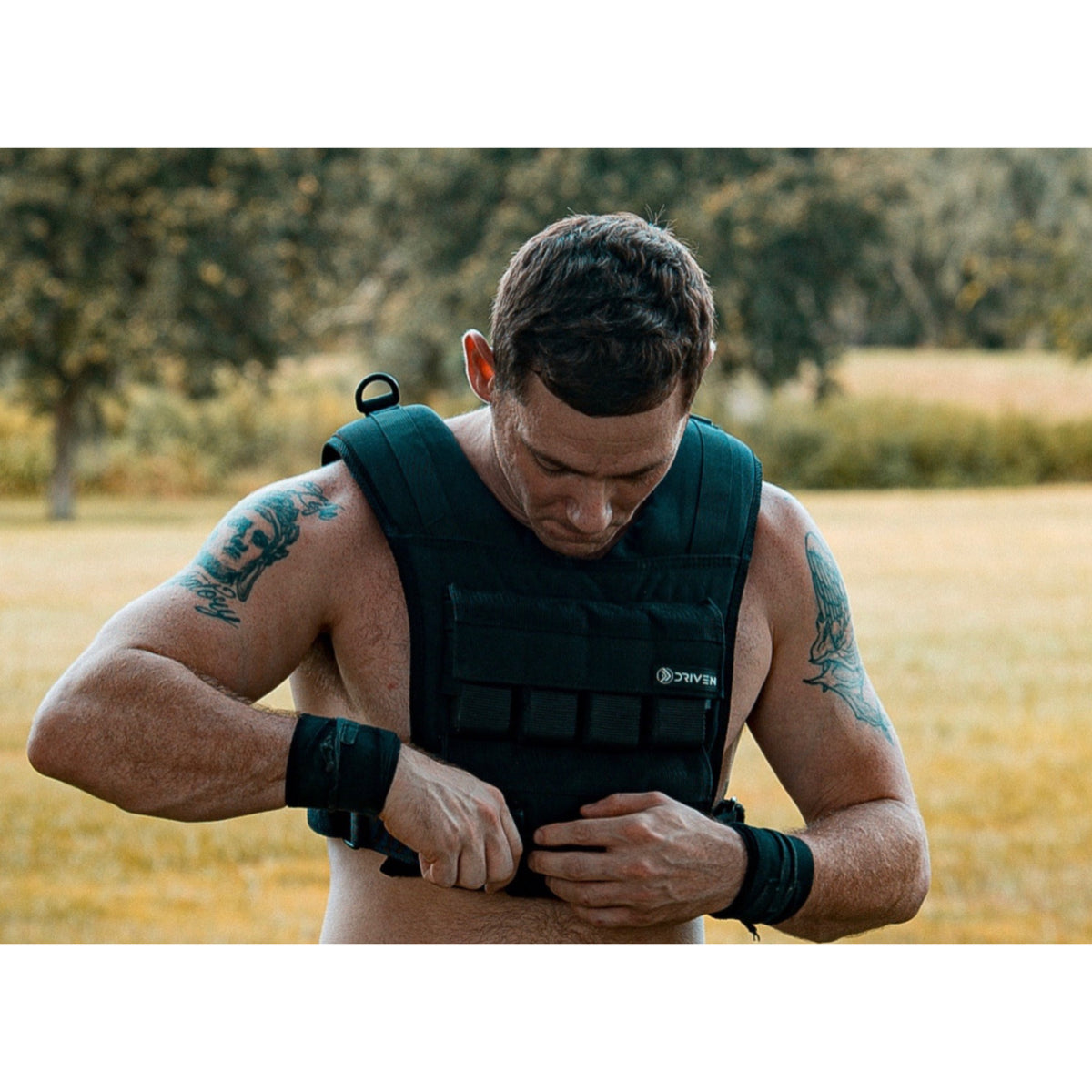 Man wearing a black weighted vest outdoors in a natural setting