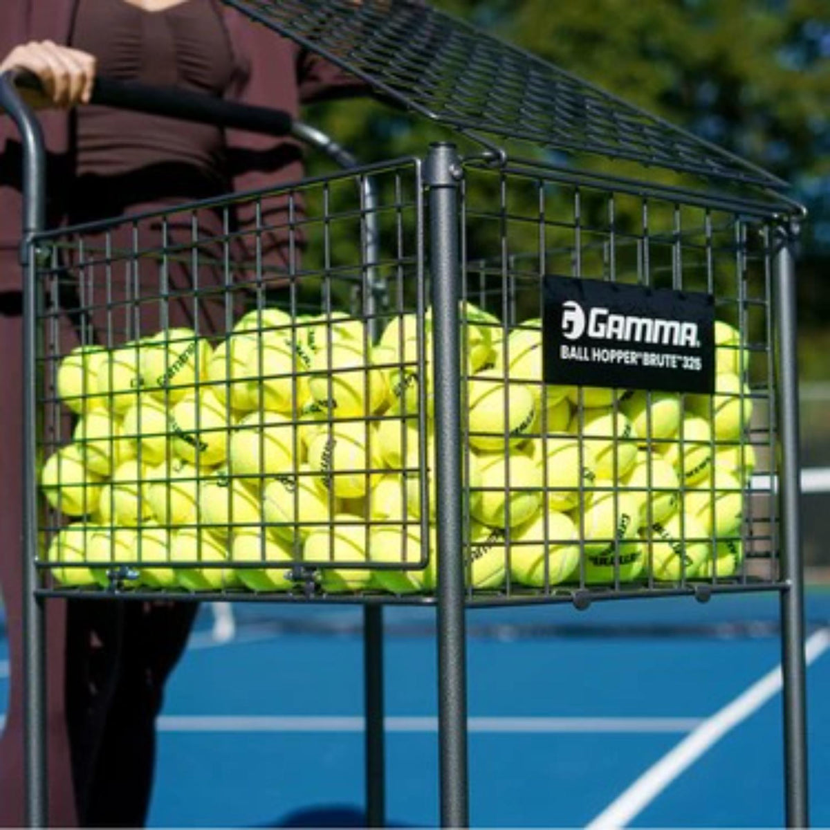 Ball hopper cart with a large wire basket, lower storage shelf, handle for transport, and four caster wheels for easy mobility.
