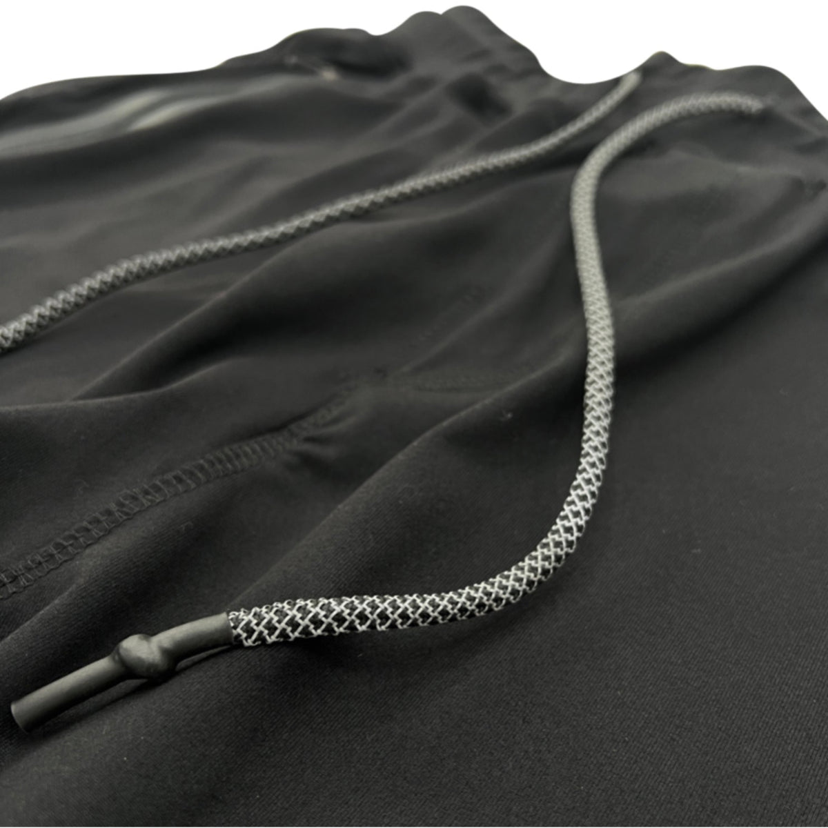 Close-up of a black drawstring with textured pattern on a black fabric background