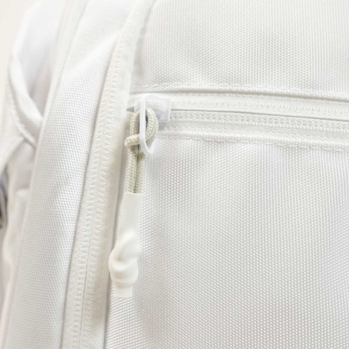 Close-up of a white backpack with a zipper detail on a light gray background