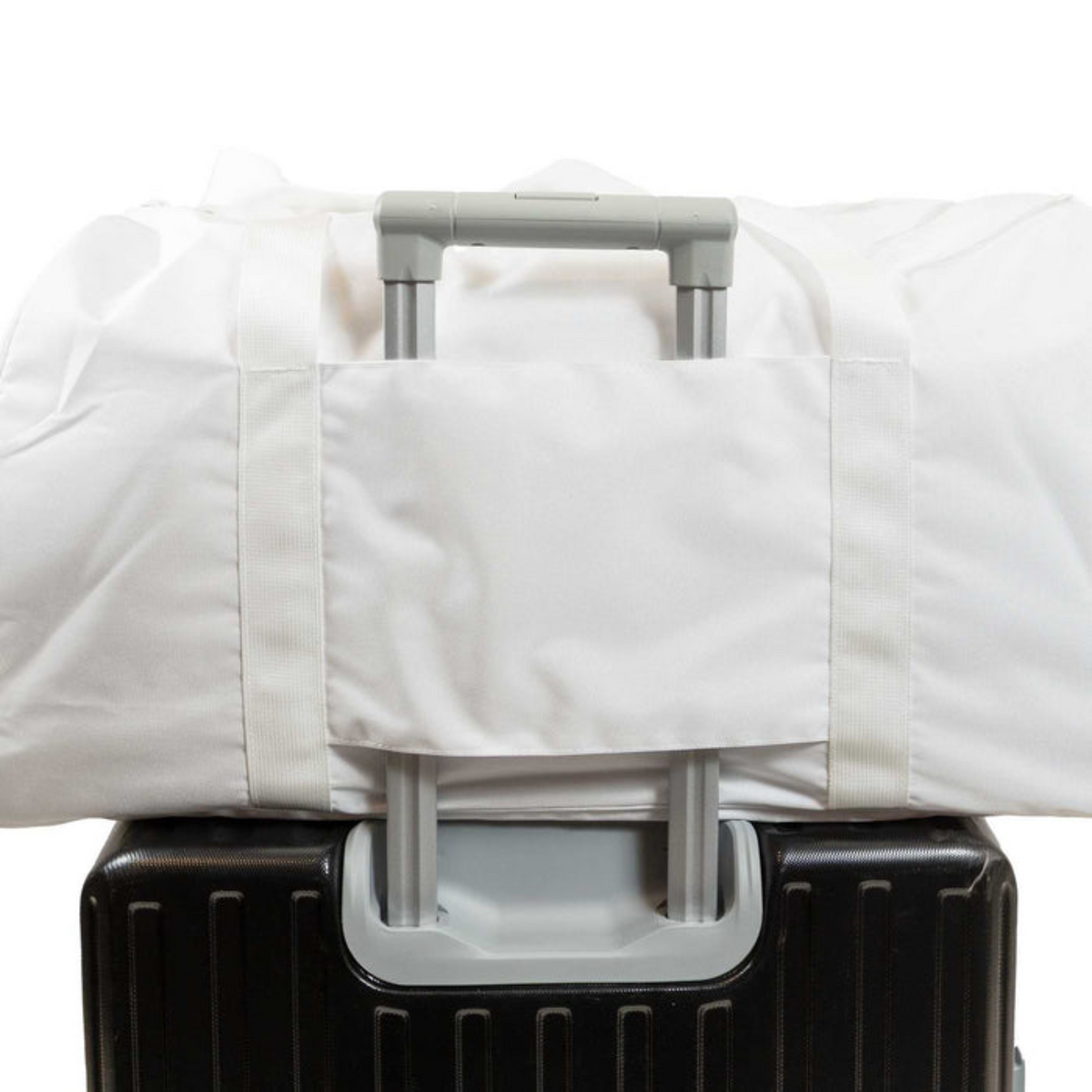 White garment bag with gray straps over a black suitcase on a white background