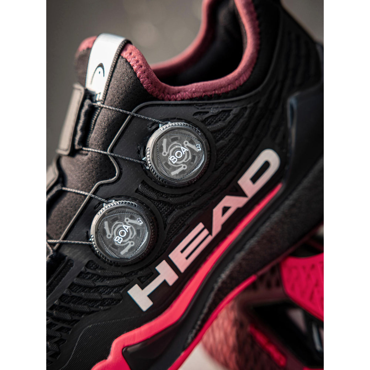 Close-up detail of a black and red HEAD Endure Pro BOA athletic shoe, highlighting the dual BOA dial closure system, textured upper, and HEAD logo on the side.