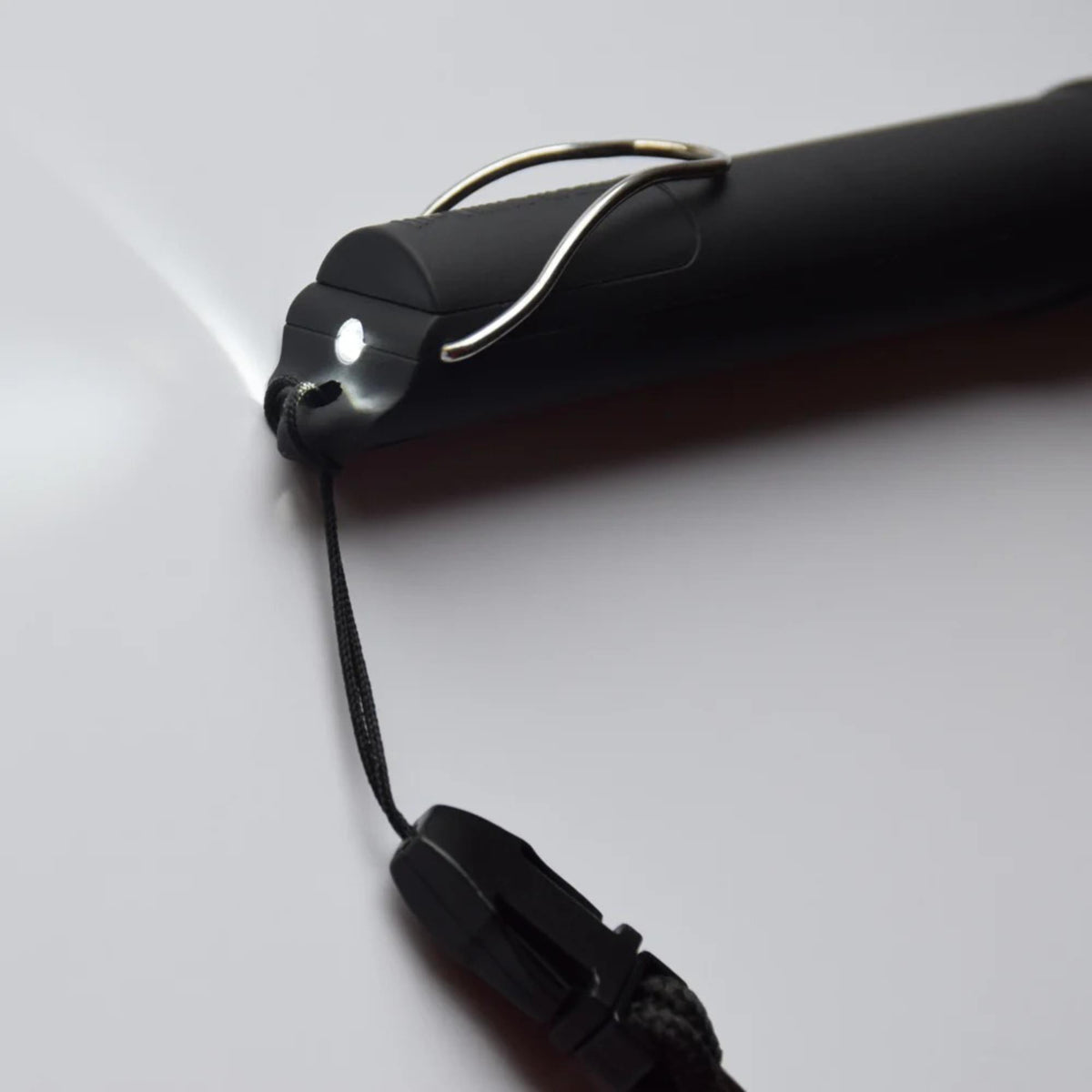 Compact electronic whistle device with push-button activation and attached lanyard for hands-free carrying and easy access.