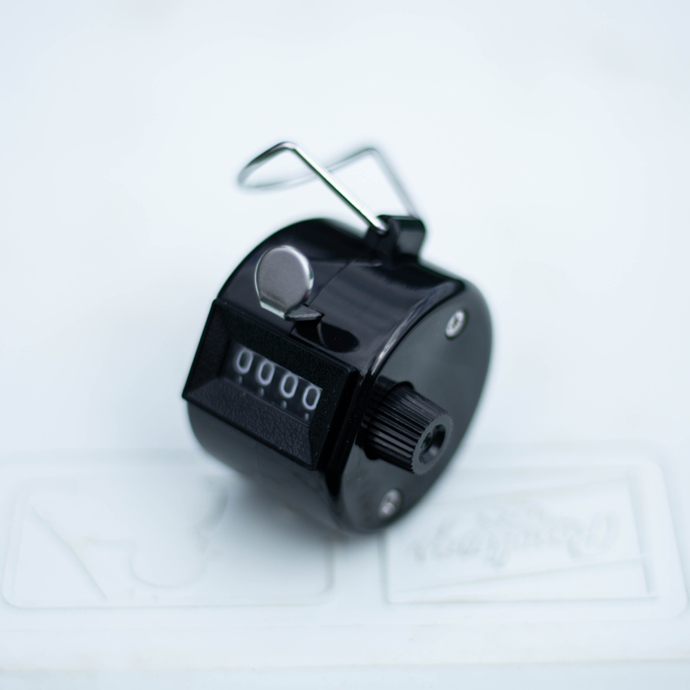 Rawlings handheld pitch counter with a black casing, metal finger loop, and manual click dial used by coaches and umpires to track pitch counts during baseball or softball games. ⚾
