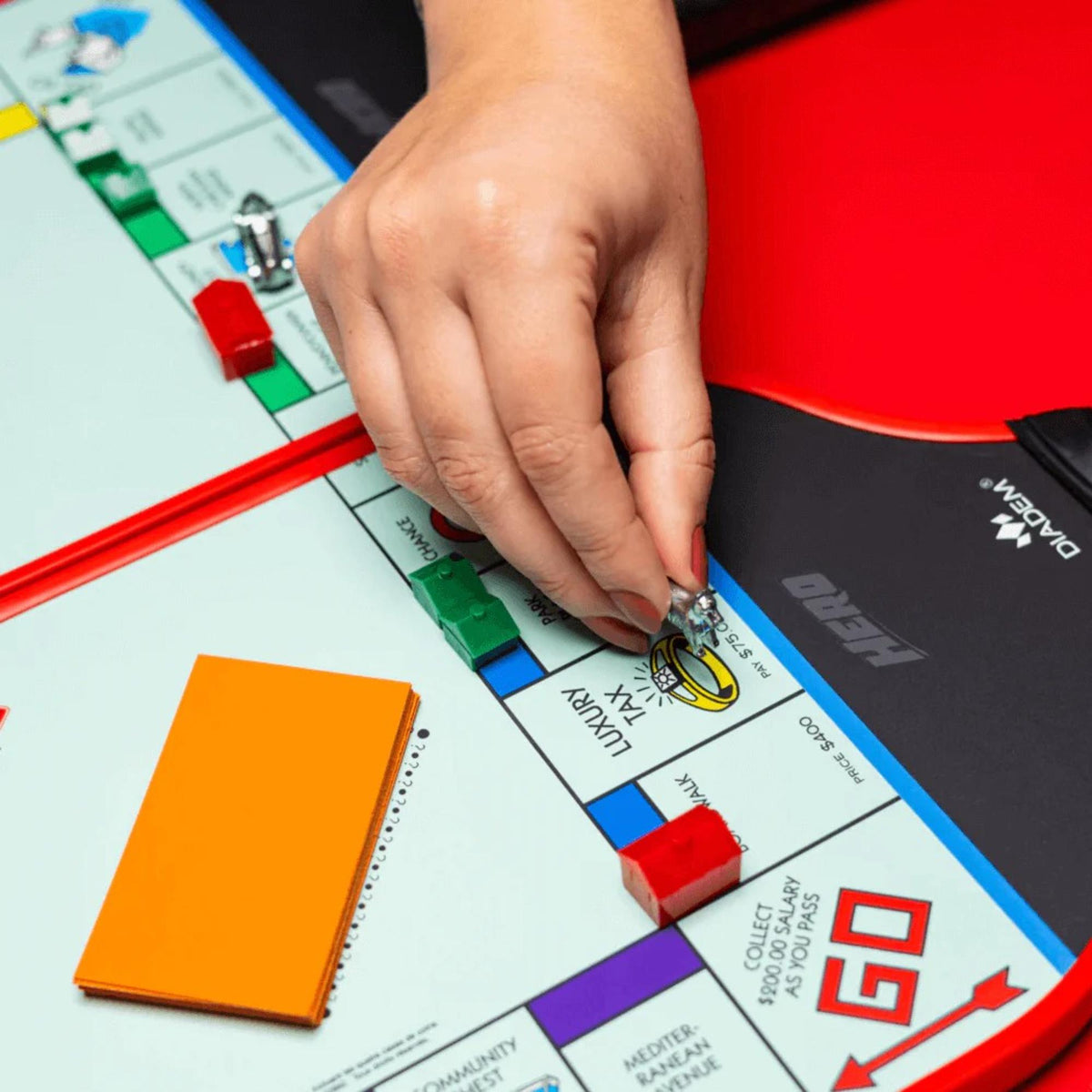 Diadem Monopoly Board 4-paddle starter kit featuring four pickleball paddles with Monopoly board-style graphics, arranged side by side with handles visible.