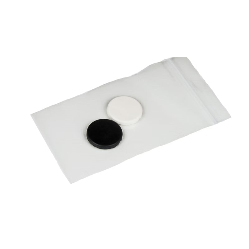 Two round black and white objects on a white sheet of paper against a white background