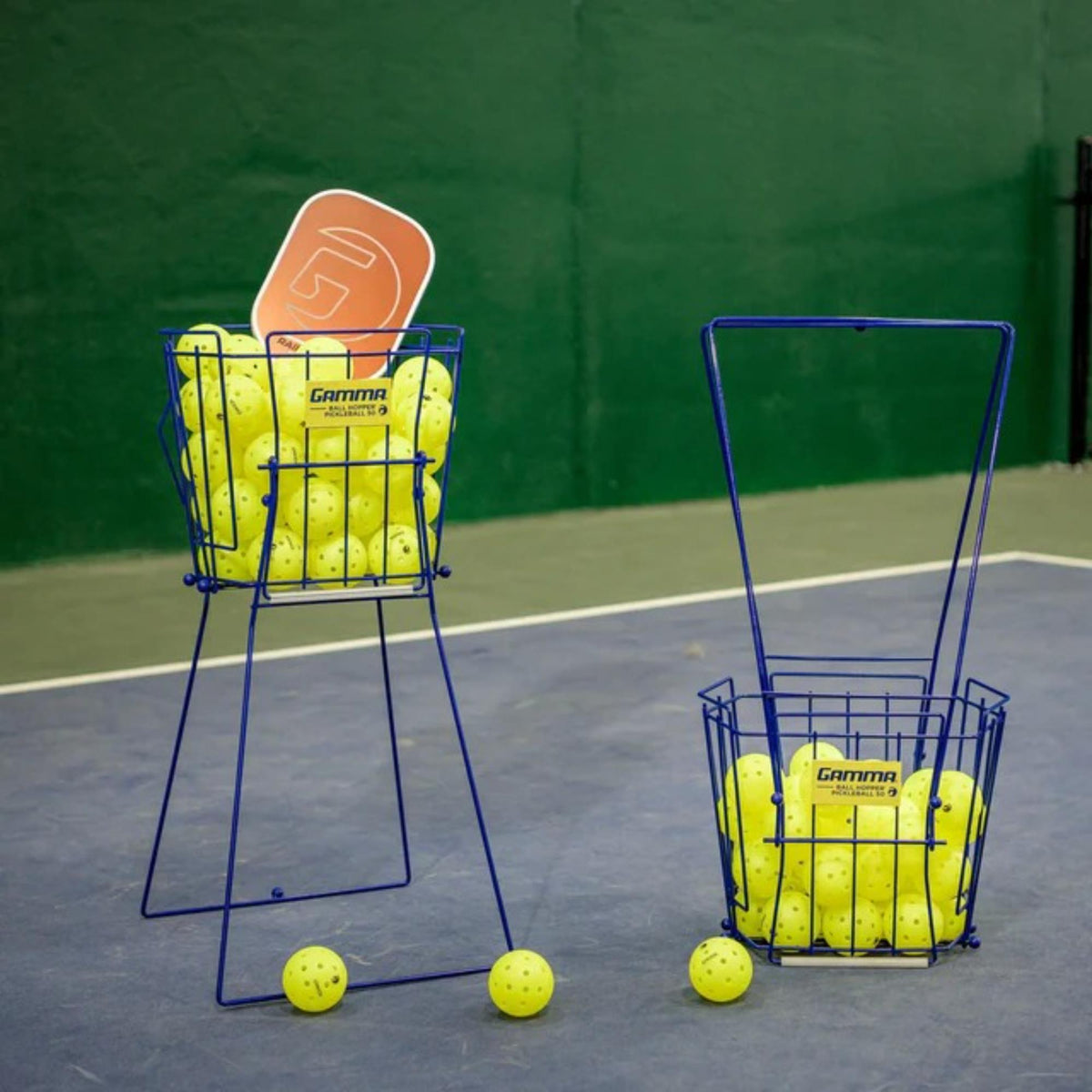 Pickleball ball hopper basket with a wire frame and carry handle, filled with balls for convenient storage and easy access during practice.