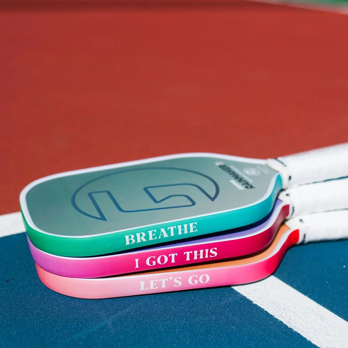 Pickleball paddle edge guard tape with gradient color designs and printed motivational text, designed to protect paddle edges from wear.