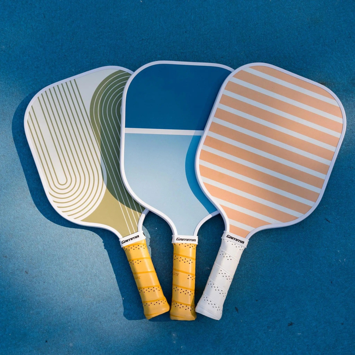 Pickleball paddle with a wide face, striped surface design, and cushioned grip handle for improved control and comfort.