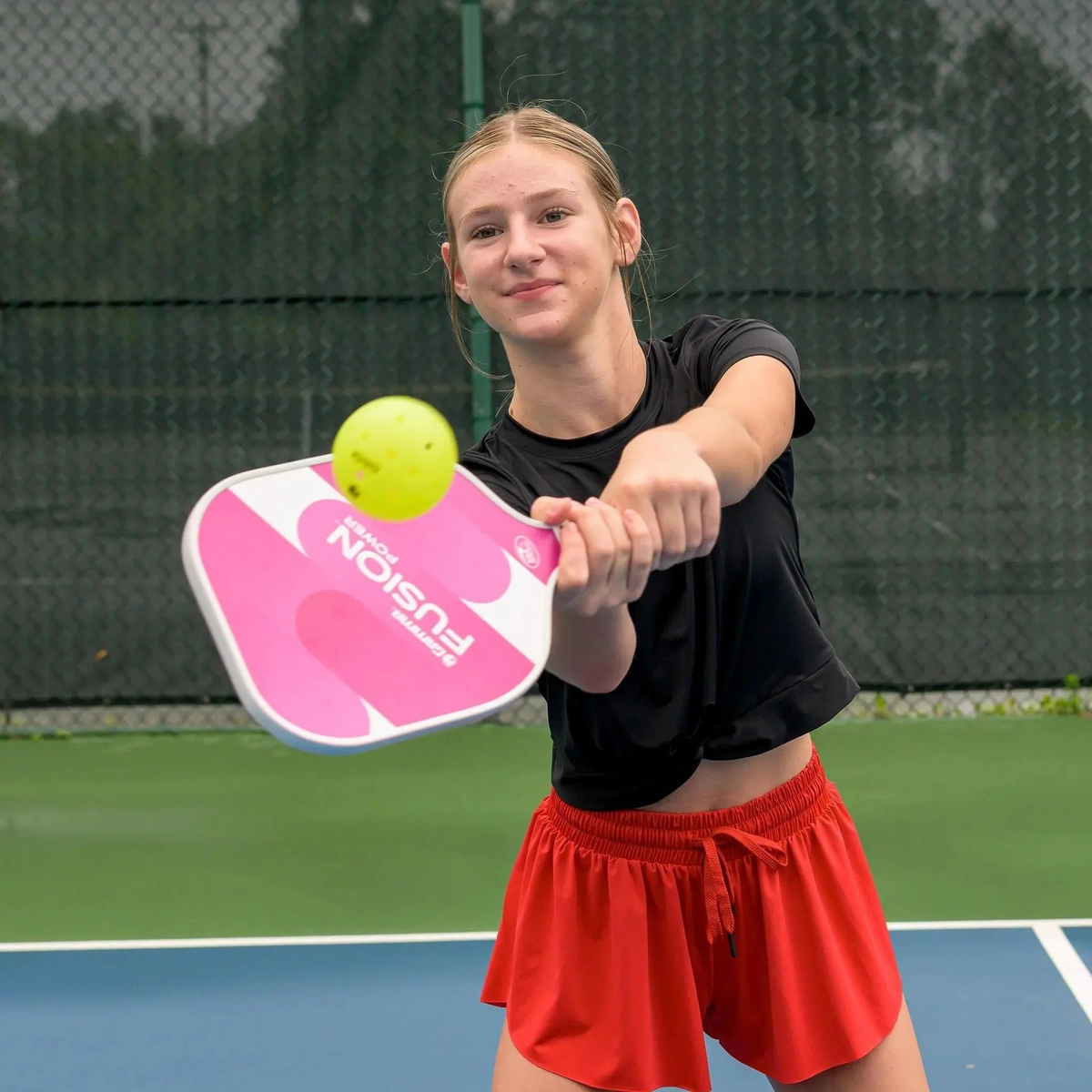 Pickleball paddle with a wide rounded face, smooth graphic design, and cushioned grip handle for enhanced power and control.