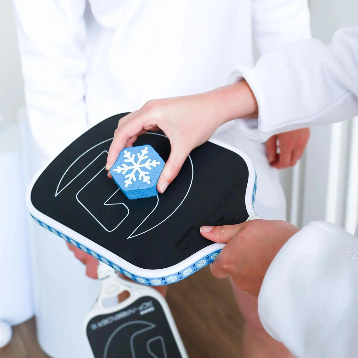 Pickleball paddle cleaning block being used on a paddle surface, designed to remove debris and maintain paddle performance.