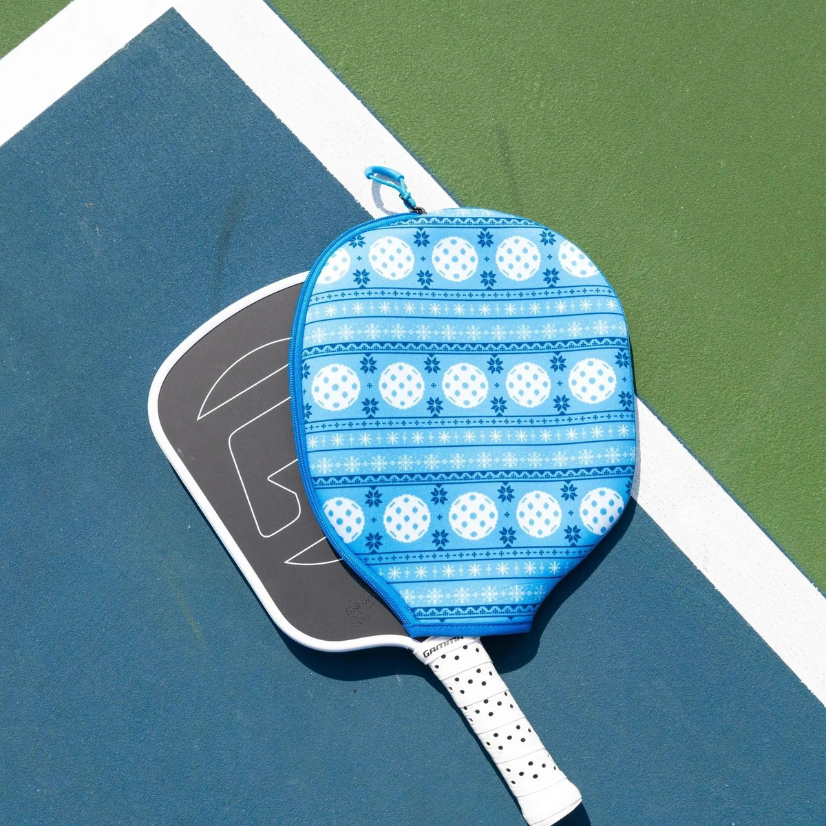 Pickleball paddle cover with a festive patterned design and zipper closure, designed to protect and store a paddle.