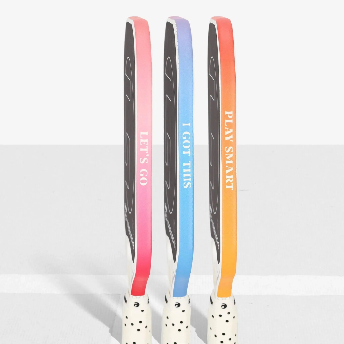 Set of pickleball paddles shown from the side featuring edge guard tape with printed motivational phrases, designed to protect paddle edges from wear and impact.