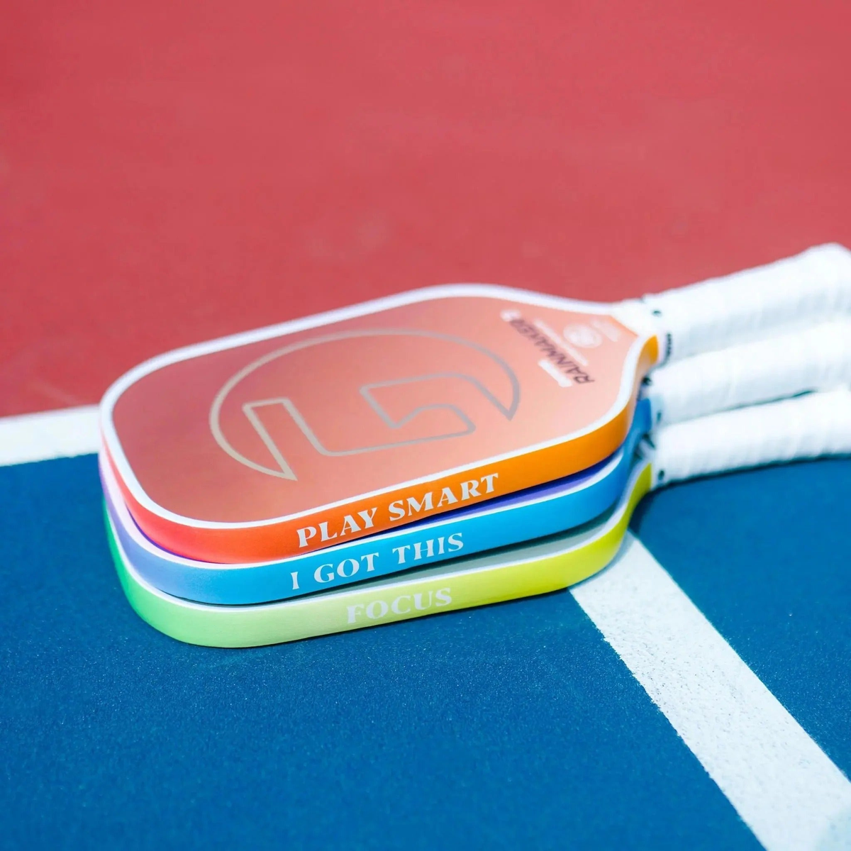 Set of pickleball paddles shown from the side featuring edge guard tape with printed motivational phrases, designed to protect paddle edges from wear and impact.