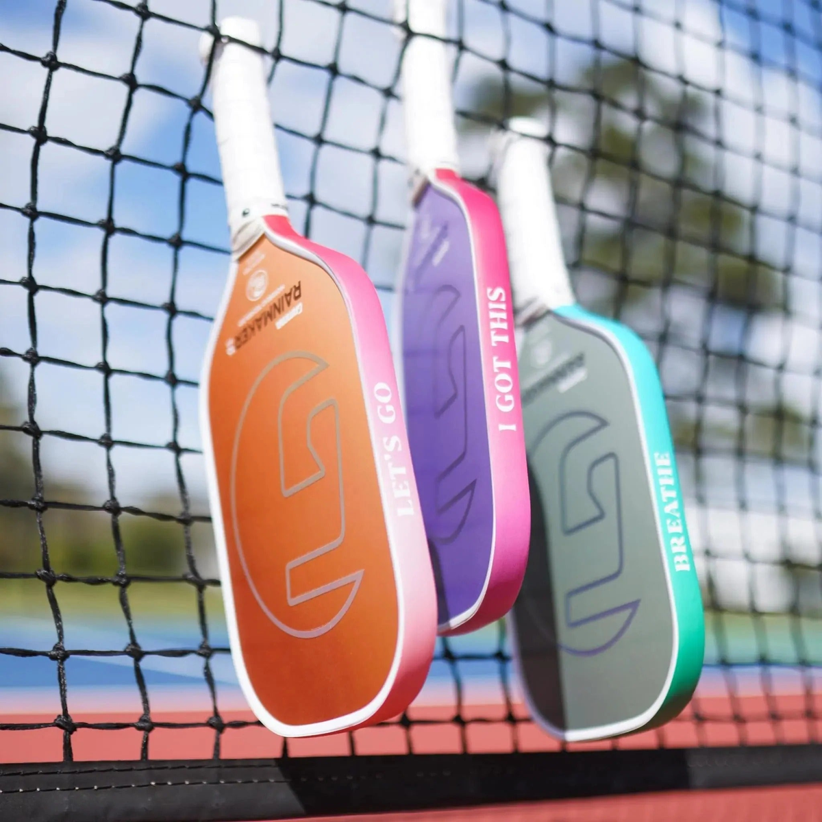 Set of pickleball paddles shown from the side featuring edge guard tape with printed motivational phrases, designed to protect paddle edges from wear and impact.