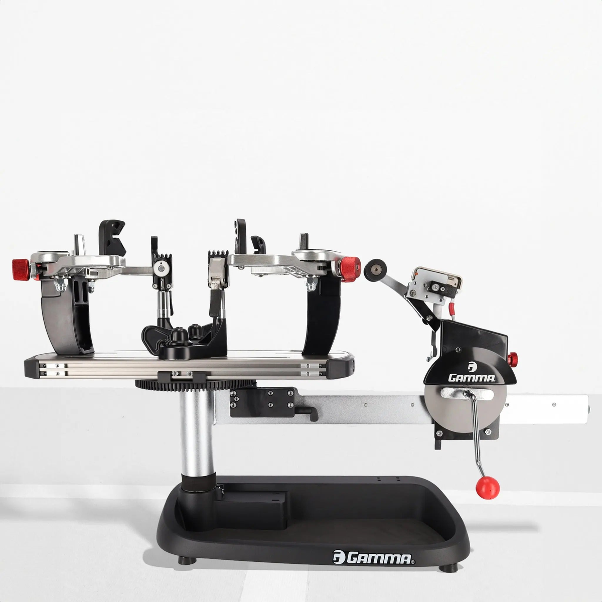 Manual spring tension stringing machine with a base platform, rotating turntable, mounting supports, and a tensioning mechanism with hand crank for securing and stringing racquets.