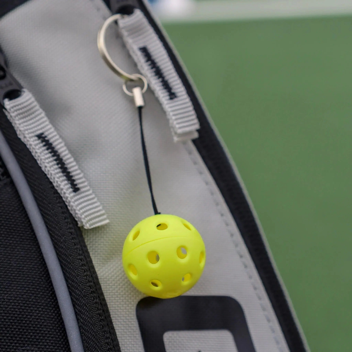 Pickleball keychain featuring a miniature perforated ball attached to a metal key ring and branded tag.