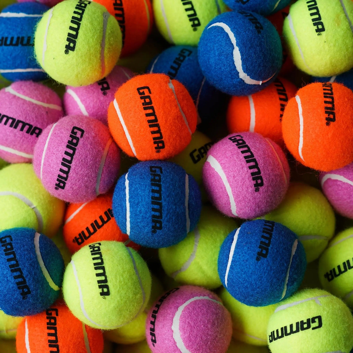 Assorted tennis balls piled together, designed for practice and long-lasting play with pressureless construction.