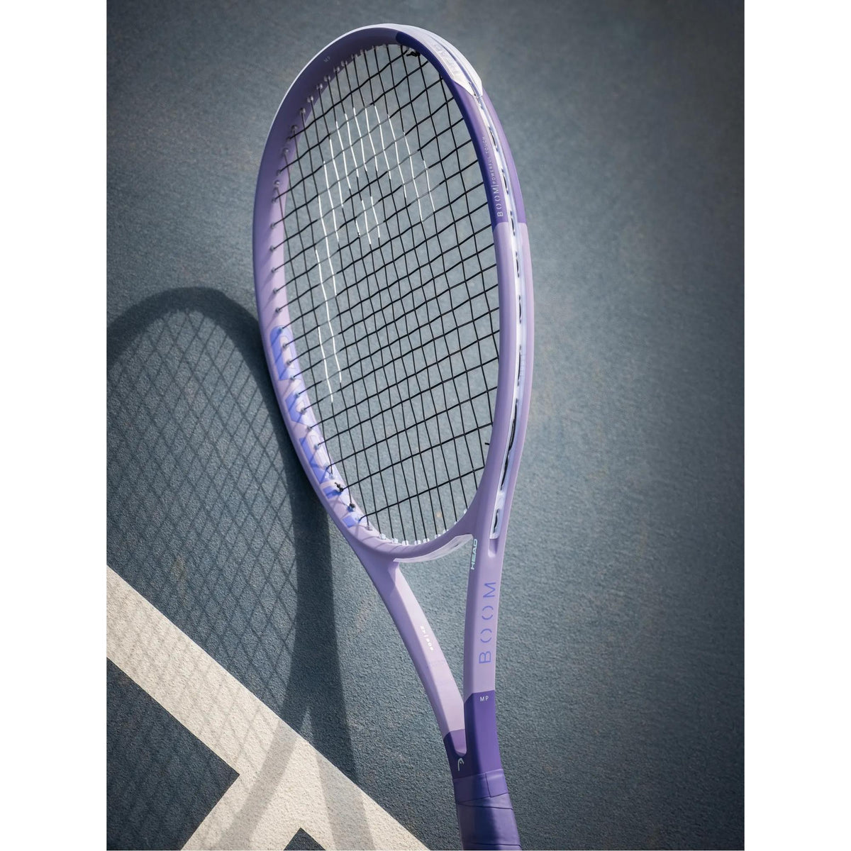 HEAD Boom Jr 25 Alternate Tennis Racquet lavender tennis racquet angled on an outdoor tennis court.