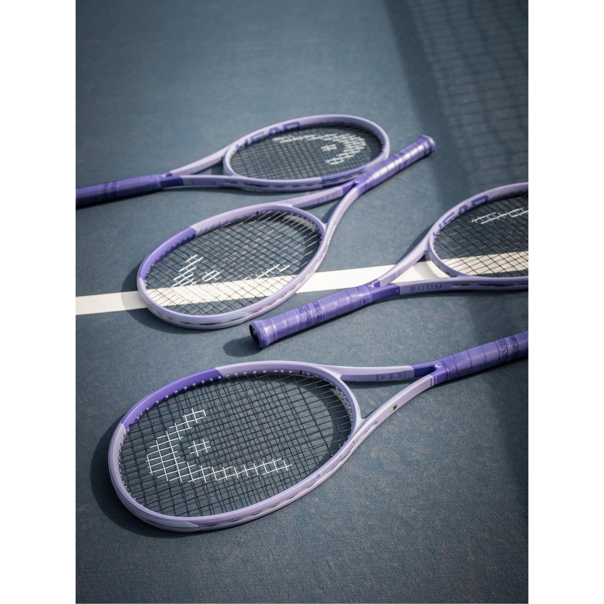 Multiple HEAD Boom Jr 25 Alternate Tennis Racquet arranged on a tennis court surface.