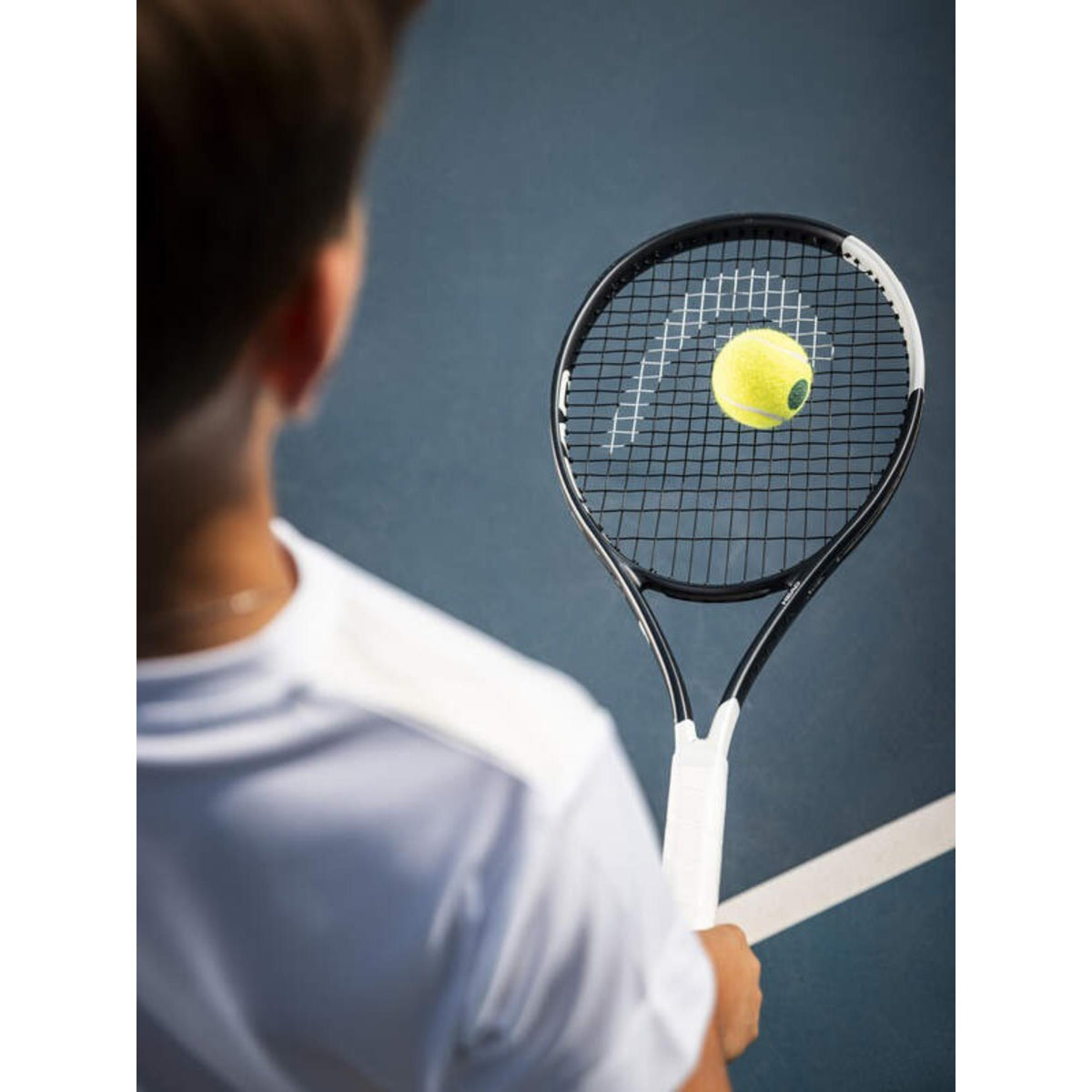 Tennis ball striking HEAD Speed Jr. 2026 racquet strings on blue court.