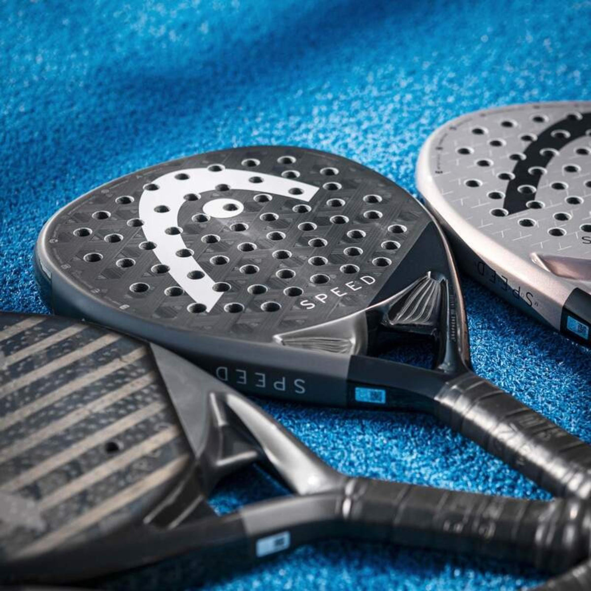 Close-up of multiple HEAD Speed padel rackets on blue court