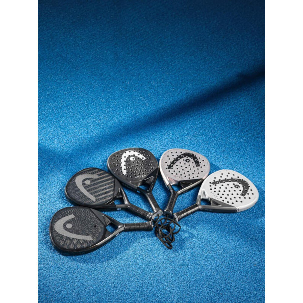 Five HEAD Speed padel rackets displayed in fan layout on blue court surface.