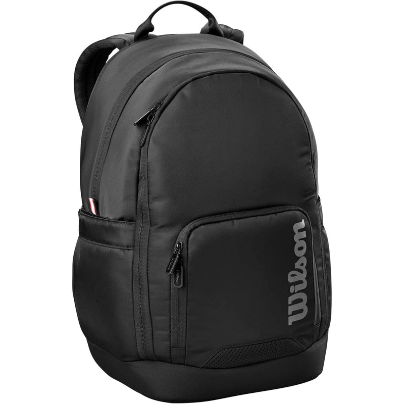 Wilson Golf Tour backpack in black with multiple zippered compartments, padded shoulder straps, and vertical Wilson logo, shown on a white background.