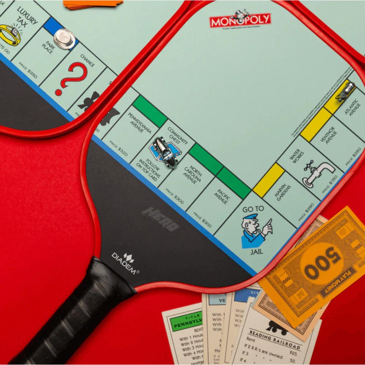 Diadem Monopoly Board 4-paddle starter kit featuring four pickleball paddles with Monopoly board-style graphics, arranged side by side with handles visible.