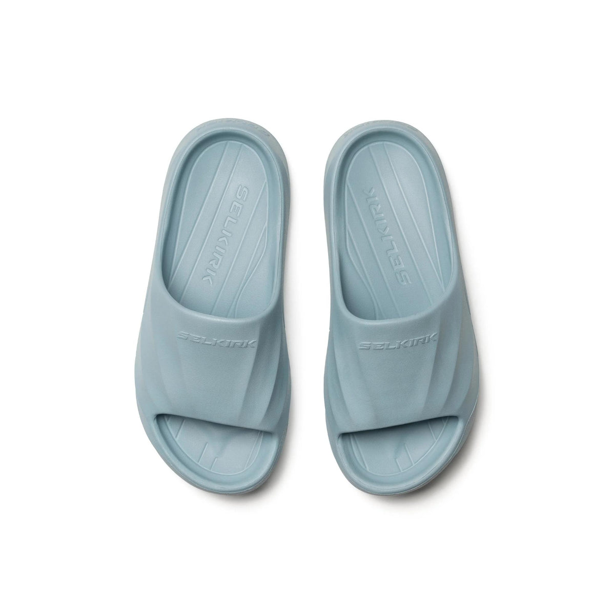 Selkirk Sport Podium pickleball slide sandals with a cushioned footbed, open-toe design, and wide strap featuring embossed branding, shown as a pair.