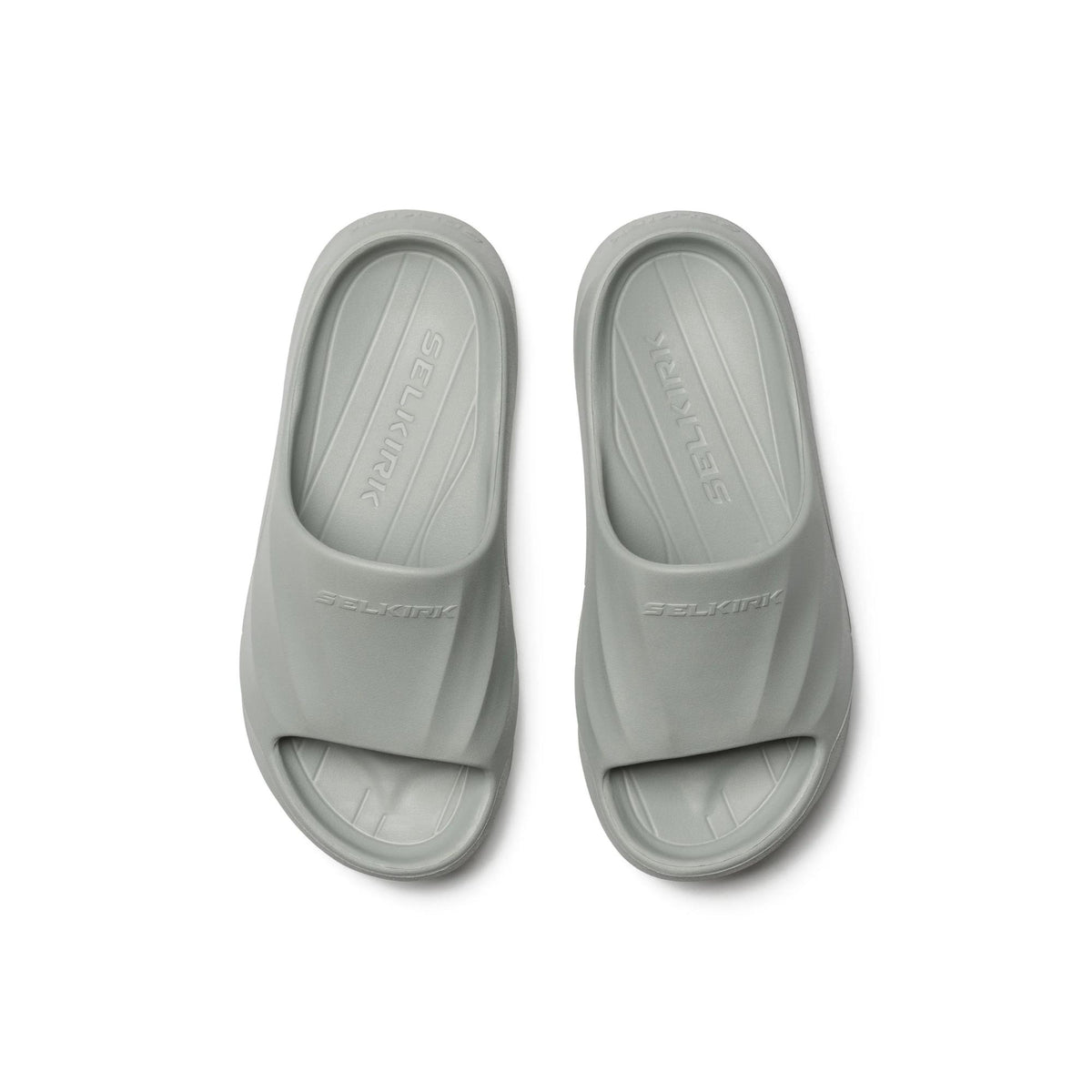 Selkirk Sport Podium pickleball slide sandals with a cushioned footbed, open-toe design, and wide strap featuring embossed branding, shown as a pair.